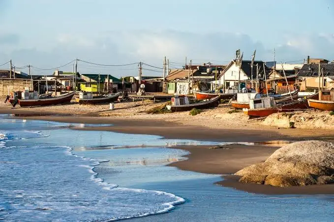 Botes de pescadores en la arena de Punta del Diablo, con el pueblo de fondo.