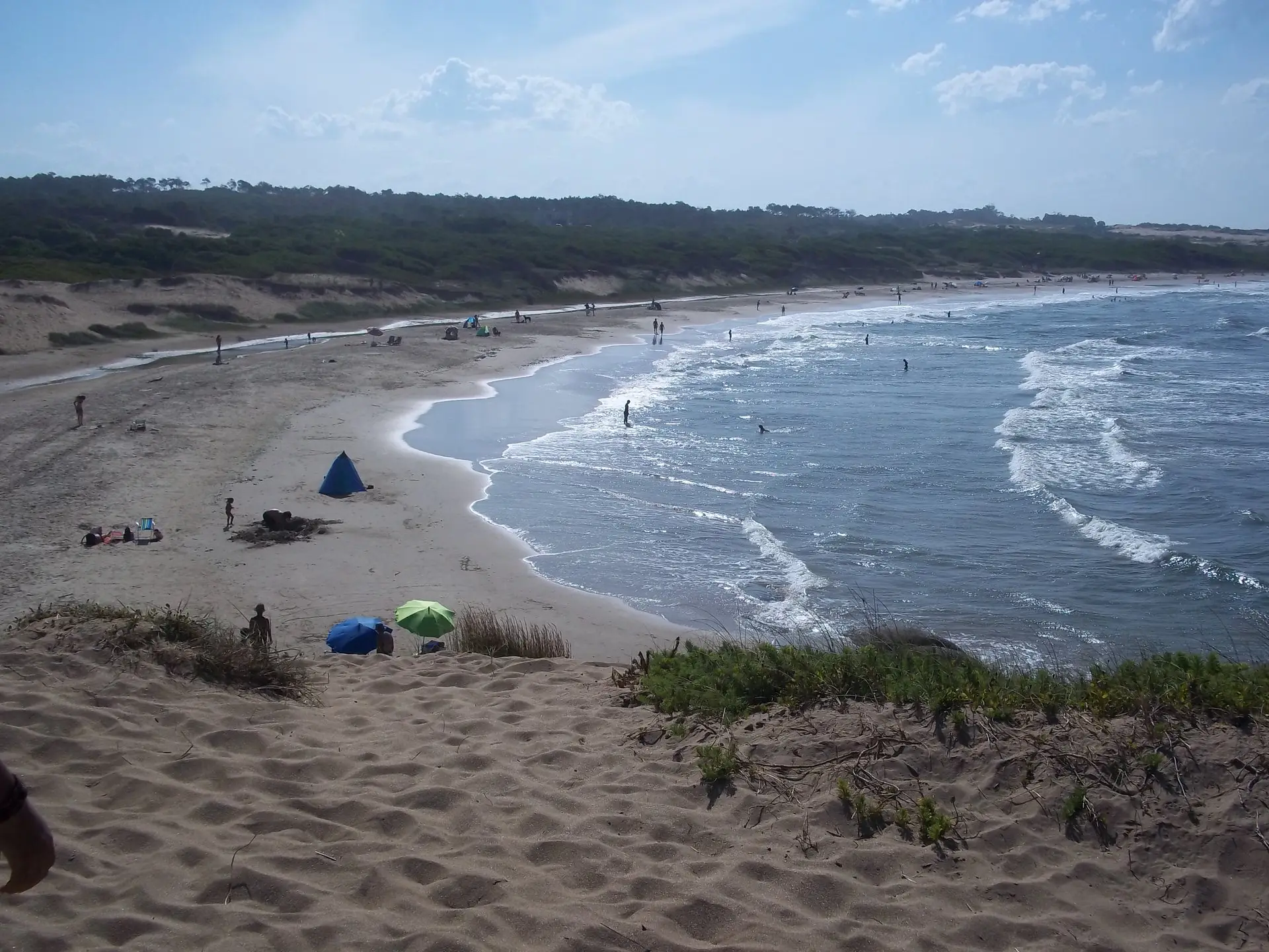Playa uruguaya en verano, con sombrillas y gente bañándose.